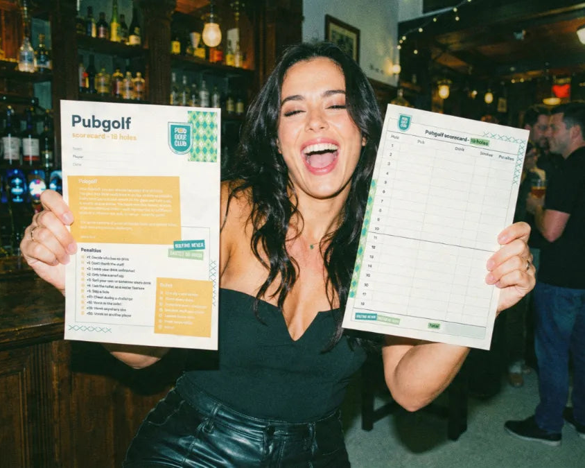 Player holding the 9 hole and 18 hole printable pub golf scorecards in a pub