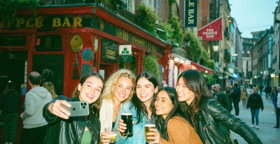 Group of friends taking a selfie with pints on a lively city-centre pub street
