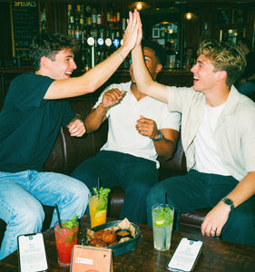 Friends high-fiving in a pub after finishing a pub golf hole